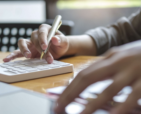 Close up Hands of businesswoman or accountant holding pen and working on calculator to calculate business data, Accountancy document and laptop computer at office, Business concept